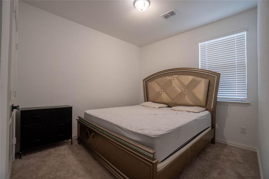Carpeted room with a ceiling-mounted light fixture, a window with horizontal blinds, and baseboard trim
