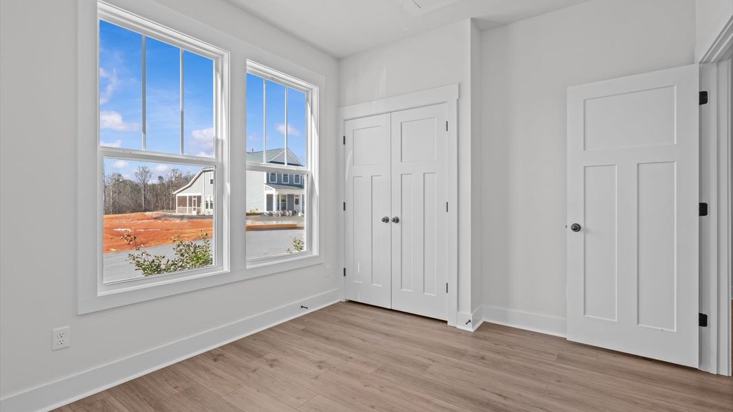 Elegant hardwood floors extend into spacious, light-filled secondary bedrooms