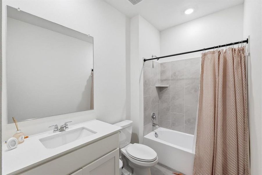 Bathroom featuring a bright white vanity with an integrated sink, polished chrome faucet, and a large wall-mounted mirror Bathroom featuring a bright white vanity with an integrated sink, polished chrome faucet, and a large wall-mounted mirror