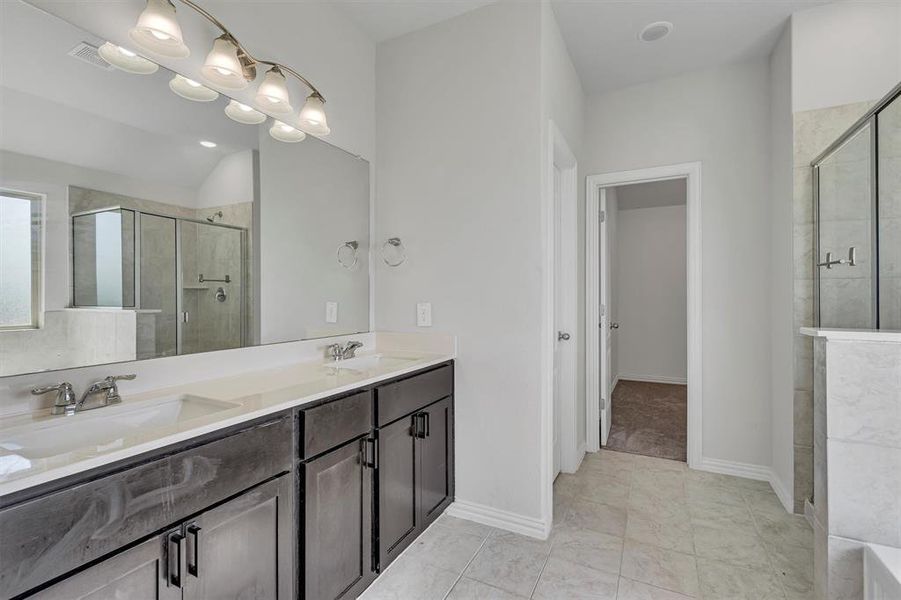 Bathroom featuring double vanity, tile patterned floors, and an enclosed shower