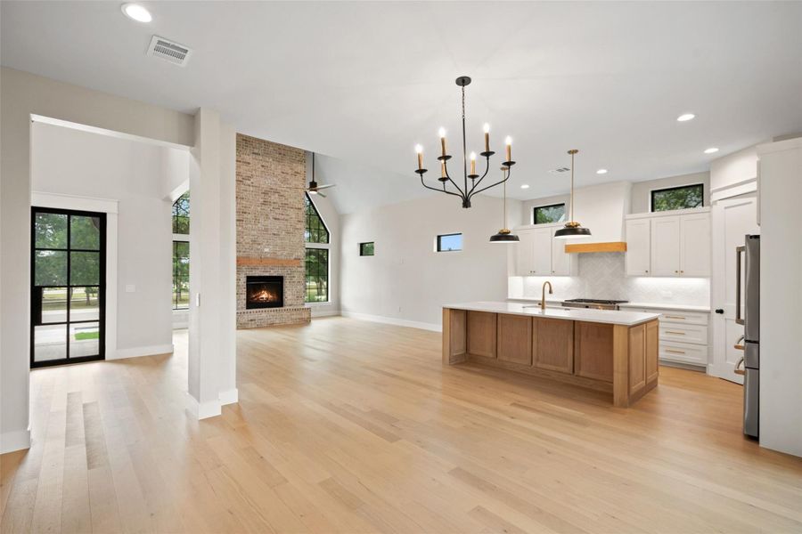 A spacious, luminous open-concept layout showcases a stately brick fireplace and a gourmet kitchen island. A spacious, luminous open-concept layout showcases a stately brick fireplace and a gourmet kitchen island.