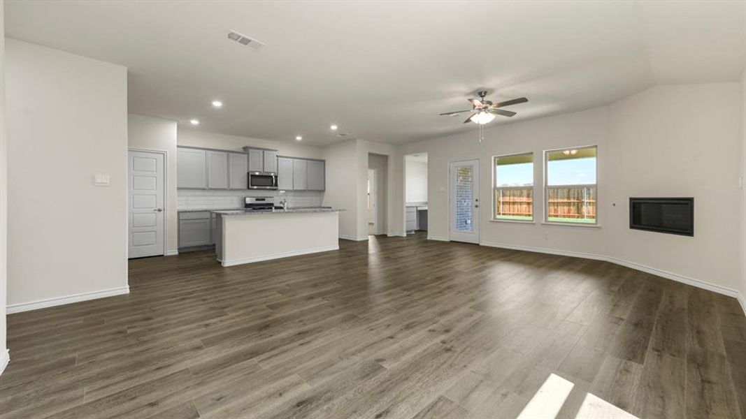 Open concept living space featuring wood-look flooring, a kitchen with light grey cabinetry and stainless steel appliances, and a fireplace