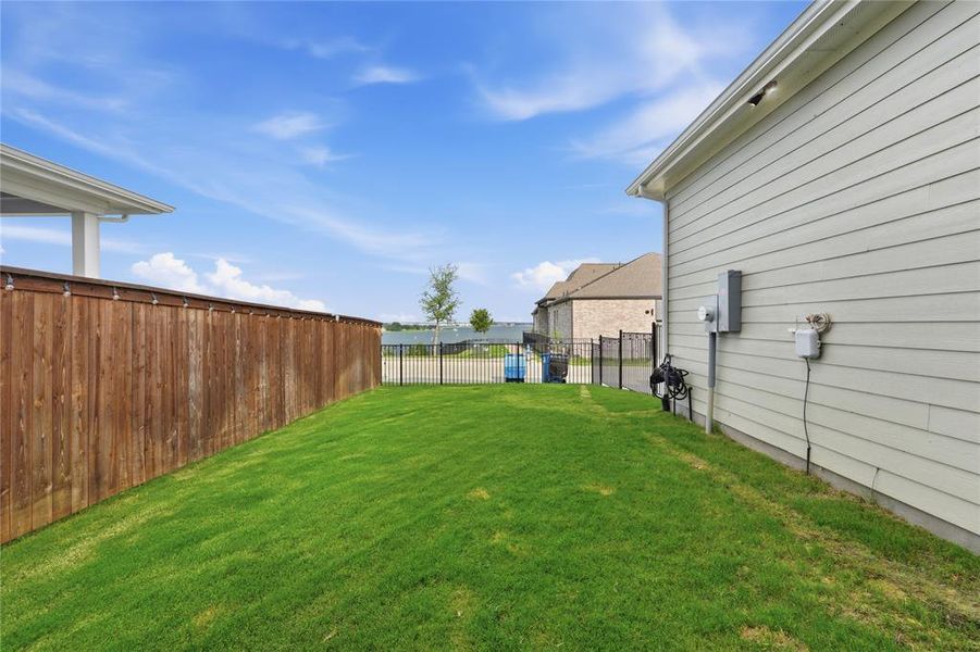 Spacious backyard featuring a manicured lawn, a stained wood privacy fence, and a black metal fence at the rear Spacious backyard featuring a manicured lawn, a stained wood privacy fence, and a black metal fence at the rear