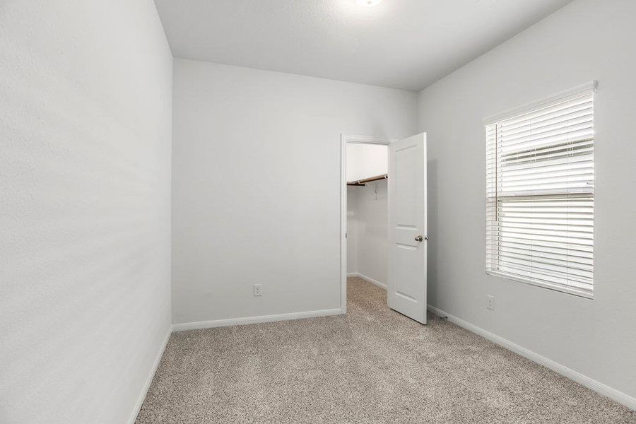 Unfurnished bedroom with light colored carpet and a spacious closet