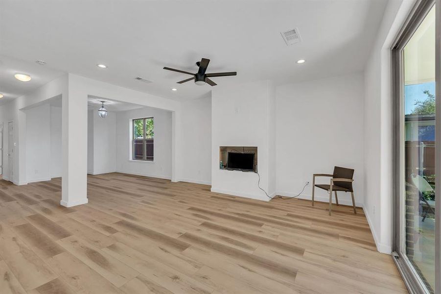 Unfurnished living room featuring light wood finished floors, recessed lighting, a fireplace, and a ceiling fan