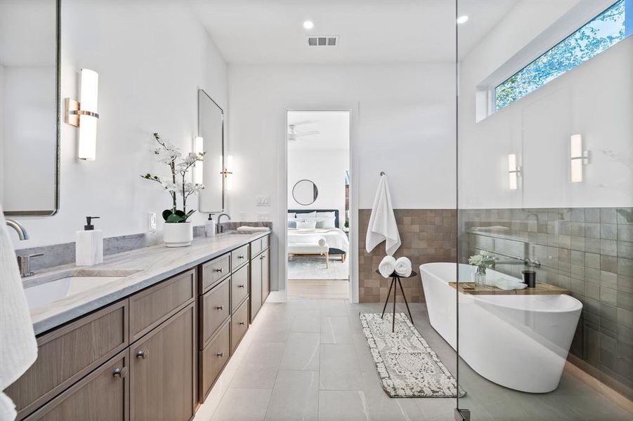 Bathroom featuring tile patterned flooring, vanity, a tub to relax in, and tile walls