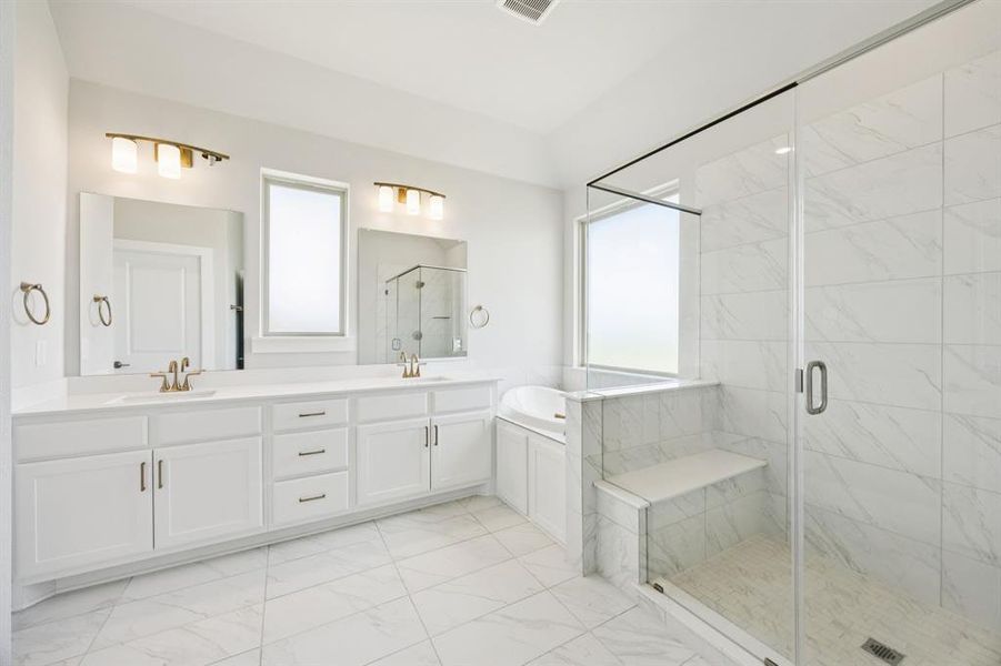 Bathroom with a marble finish shower, double vanity, light marble finish flooring, and a bath