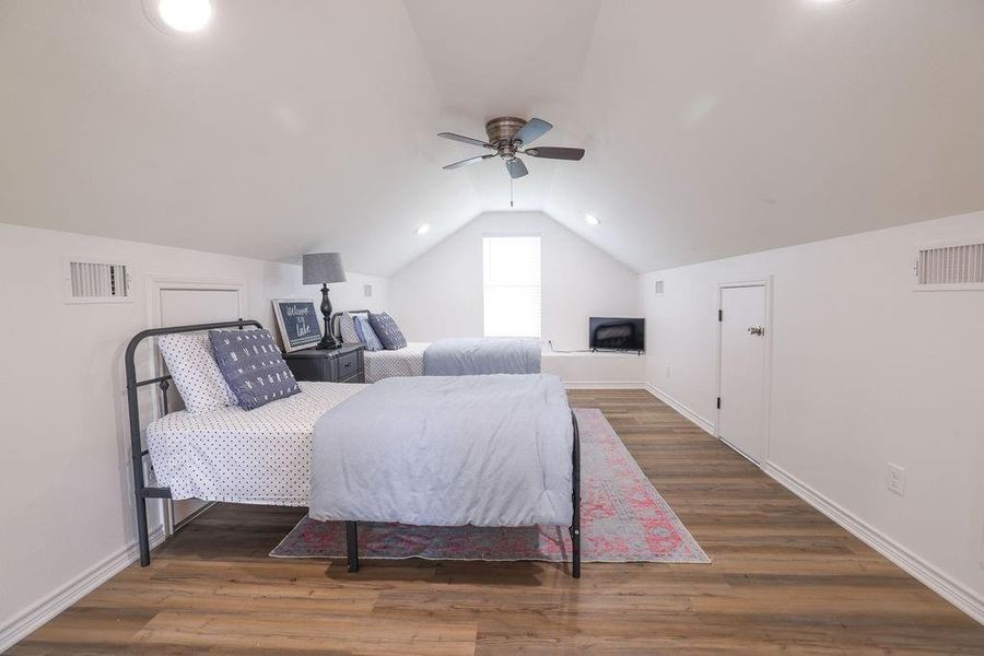 Bedroom featuring lofted ceiling, wood finished floors, and a ceiling fan