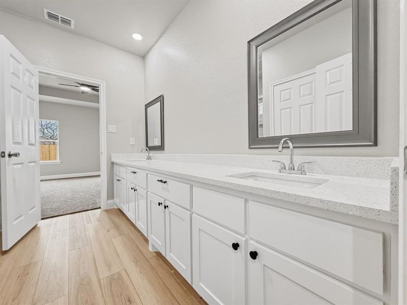 Bathroom featuring double vanity, light wood-type flooring, and recessed lighting
