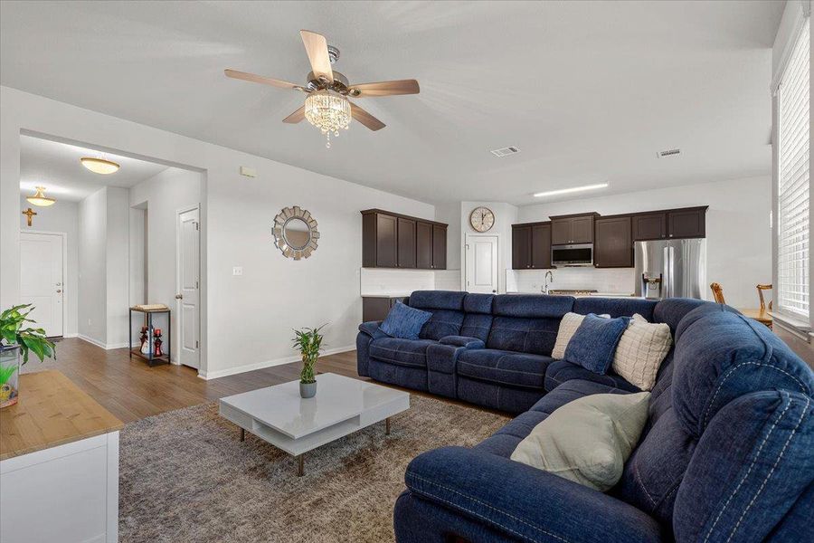 An open-concept living area displays rich wood flooring and transitions smoothly into the kitchen.