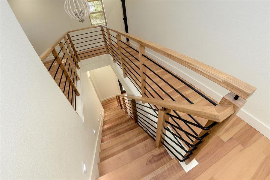 Stairway featuring wood finished floors and a chandelier