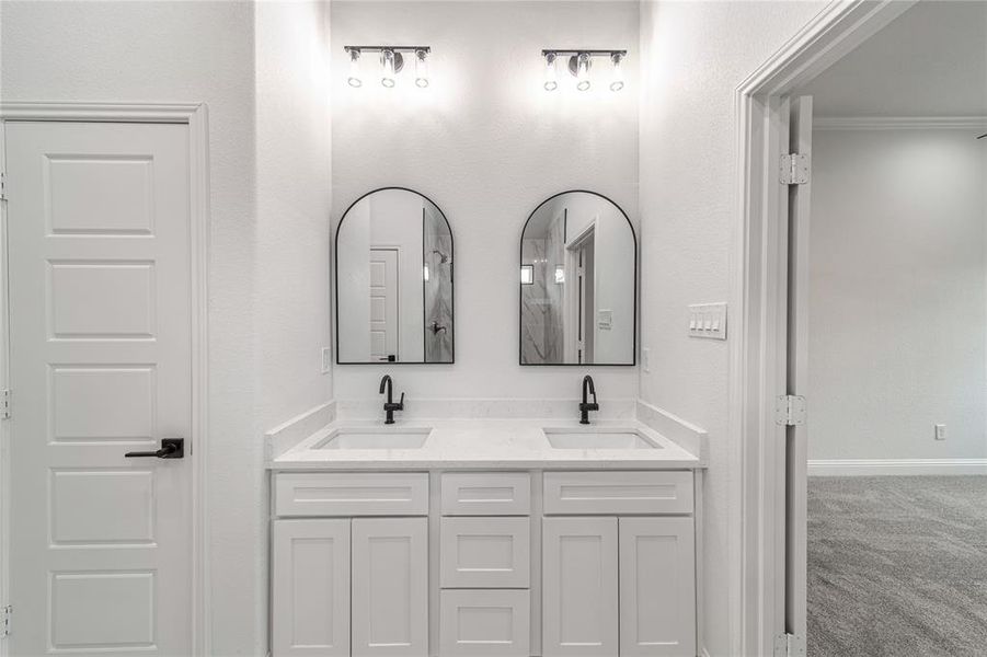 Full bath featuring double vanity, crown molding, baseboards, and a sink