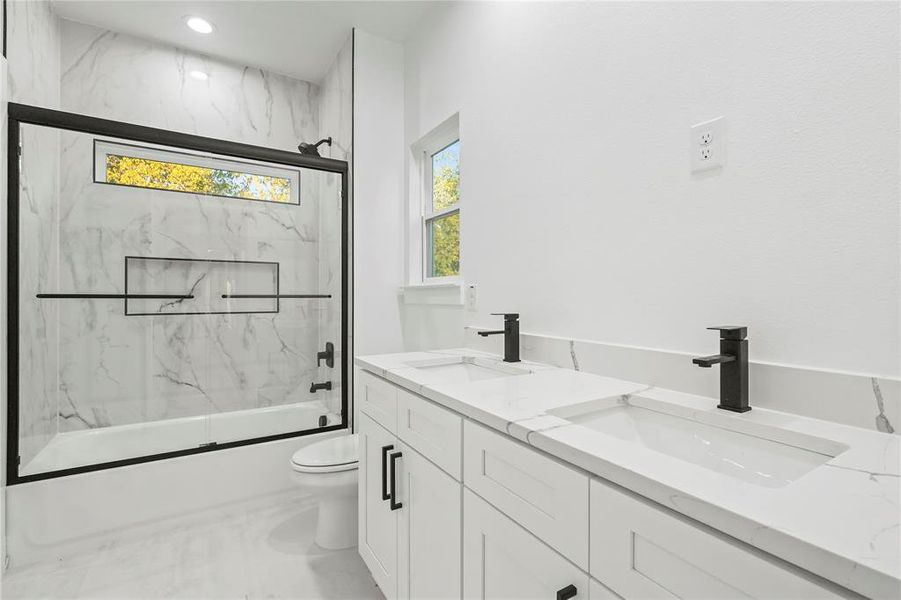 Bathroom featuring double vanity and bath / shower combo with glass door Bathroom featuring double vanity and bath / shower combo with glass door
