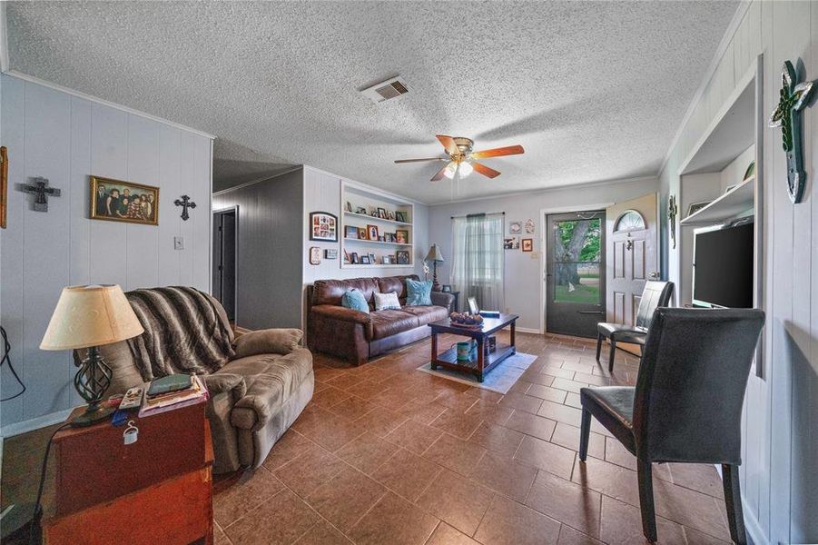 Living room featuring ceiling fan and a textured ceiling