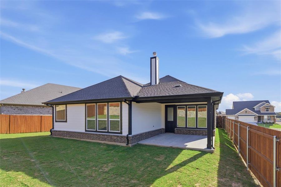 Back of property featuring a fenced backyard, a shingled roof, brick siding, a patio, and a chimney