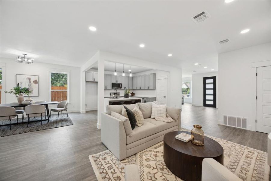 Living room with wood-style floors, open to the kitchen, dining area and back patio