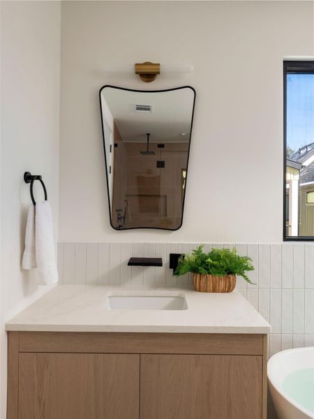 Bathroom featuring a stall shower, vanity, and tile walls
