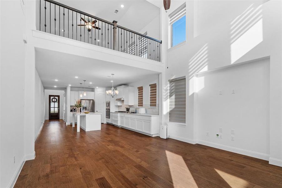 Unfurnished living room with a high ceiling, an inviting chandelier, and dark hardwood / wood-style flooring