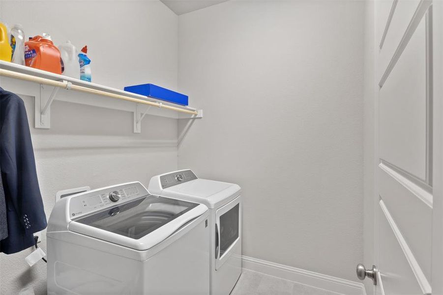 Clothes washing area featuring light tile patterned floors and washing machine and dryer