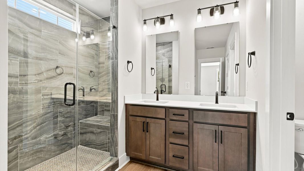 Notable primary bath featuring dual vanity, walk-in shower, and tasteful design touches throughout by DRB Homes