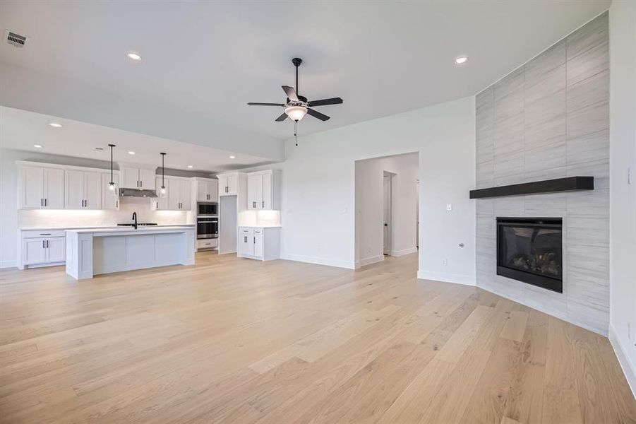 Unfurnished living room with a sink, a ceiling fan, recessed lighting, a tiled fireplace, and baseboards Unfurnished living room with a sink, a ceiling fan, recessed lighting, a tiled fireplace, and baseboards