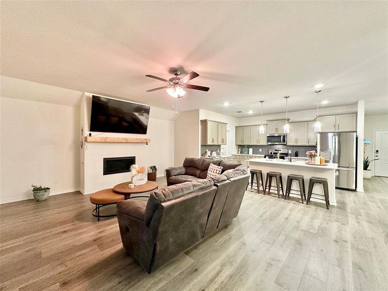 Living area with a fireplace, light wood-type flooring, recessed lighting, and ceiling fan Living area with a fireplace, light wood-type flooring, recessed lighting, and ceiling fan