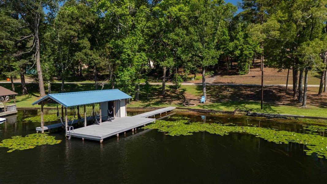 Private covered boat dock with a blue metal roof, an attached pier, and a boat lift