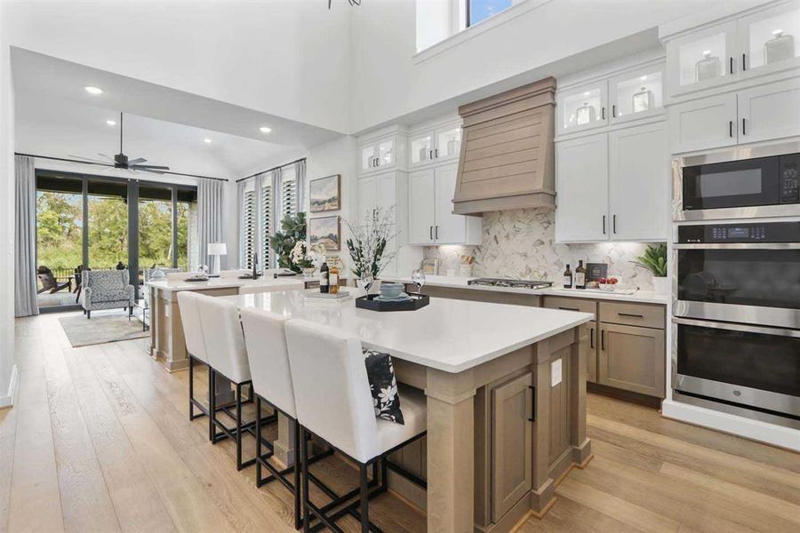 Kitchen featuring white cabinets, stainless steel appliances, tasteful backsplash, a kitchen breakfast bar, and a large island