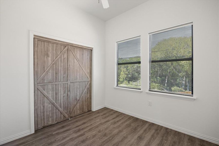 Unfurnished bedroom featuring dark wood-type flooring and ceiling fan