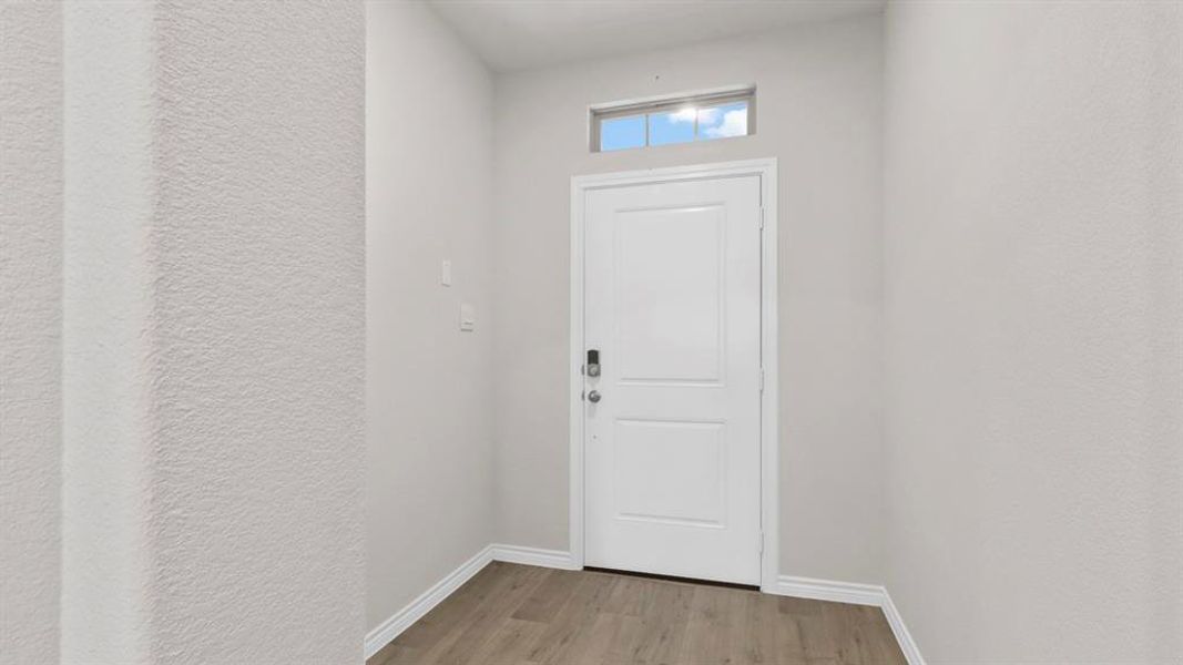 Doorway with a textured wall and wood finished floors