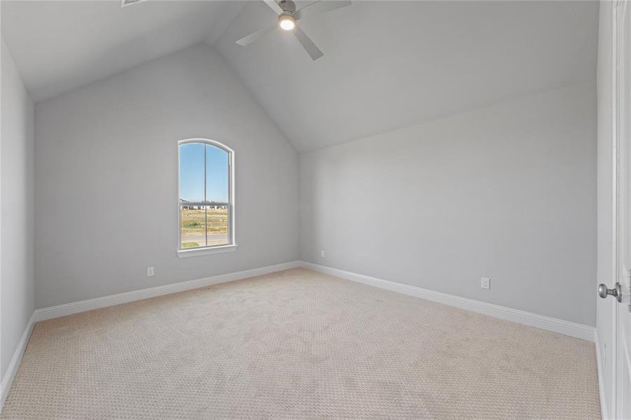 Guest bedroom featuring lofted ceiling, light colored carpet, and ceiling fan