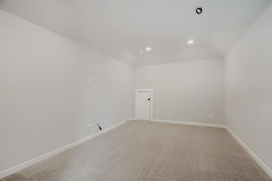 Spacious room featuring neutral carpeting, light-toned walls, and recessed lighting fixtures