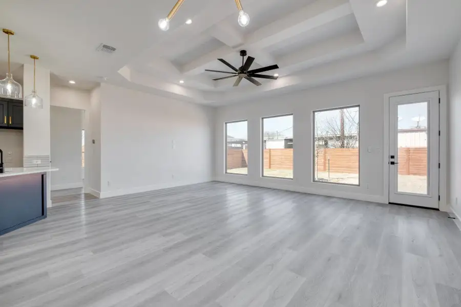 Unfurnished living room featuring a tray ceiling, recessed lighting, baseboards, and light wood finished floors