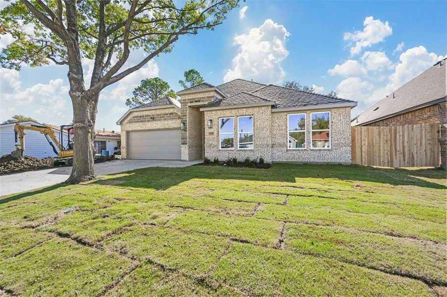 View of front of property featuring a front lawn and a garage