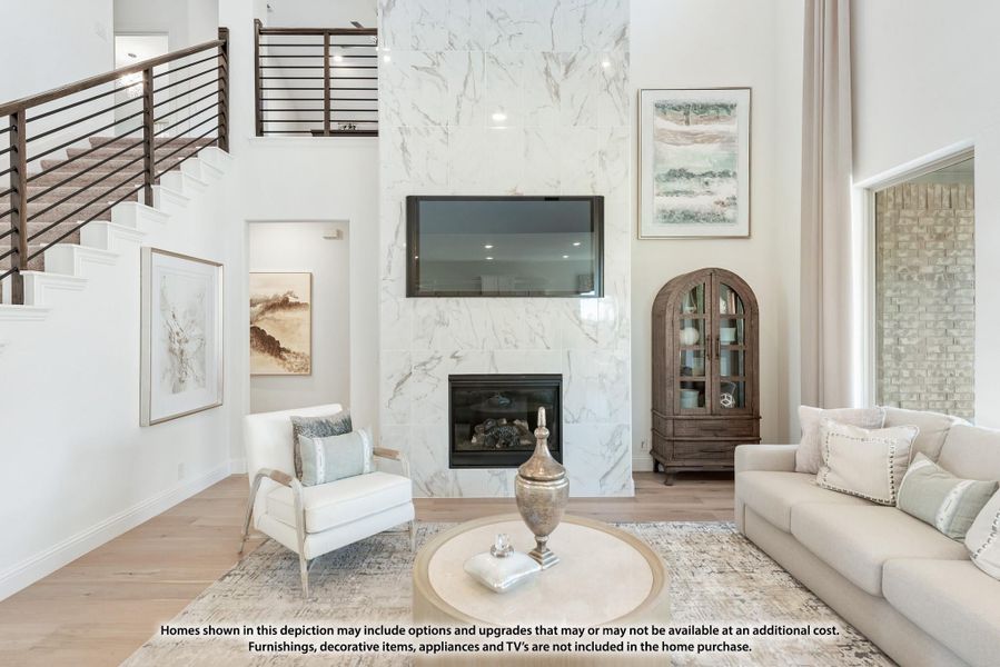 Two-story living room with marble fireplace surround, wall-mounted TV, and open staircase with wood railings Two-story living room with marble fireplace surround, wall-mounted TV, and open staircase with wood railings