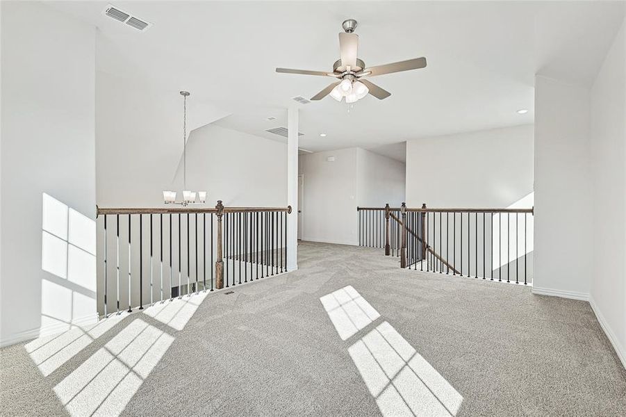 Unfurnished room with carpet flooring, a ceiling fan, and suspended lighting