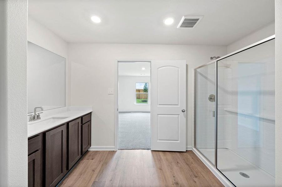Bathroom with light wood-style floors, vanity, recessed lighting, and a shower stall