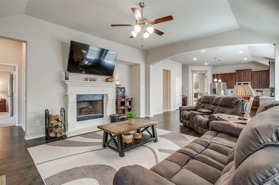 Living room with ceiling fan, dark wood-type flooring, and vaulted ceiling