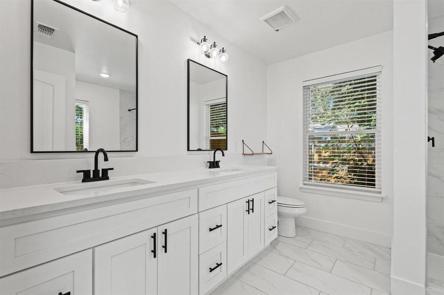 Full bathroom with double vanity, a marble finish shower, and light marble finish floors