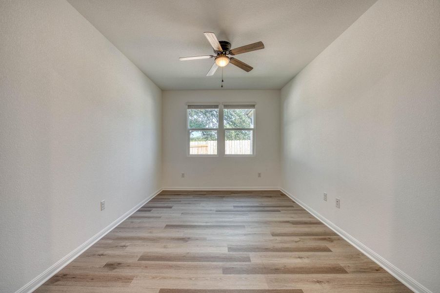 Smooth wood-look flooring and clean neutral walls frame a versatile secondary bedroom space.