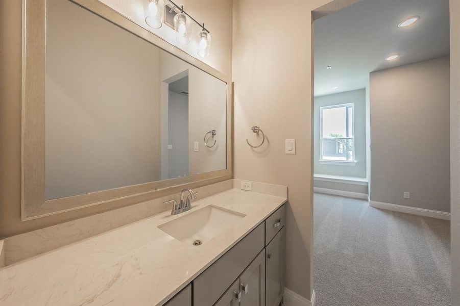 Modern bathroom vanity featuring a light-colored countertop, an integrated sink, and a framed mirror