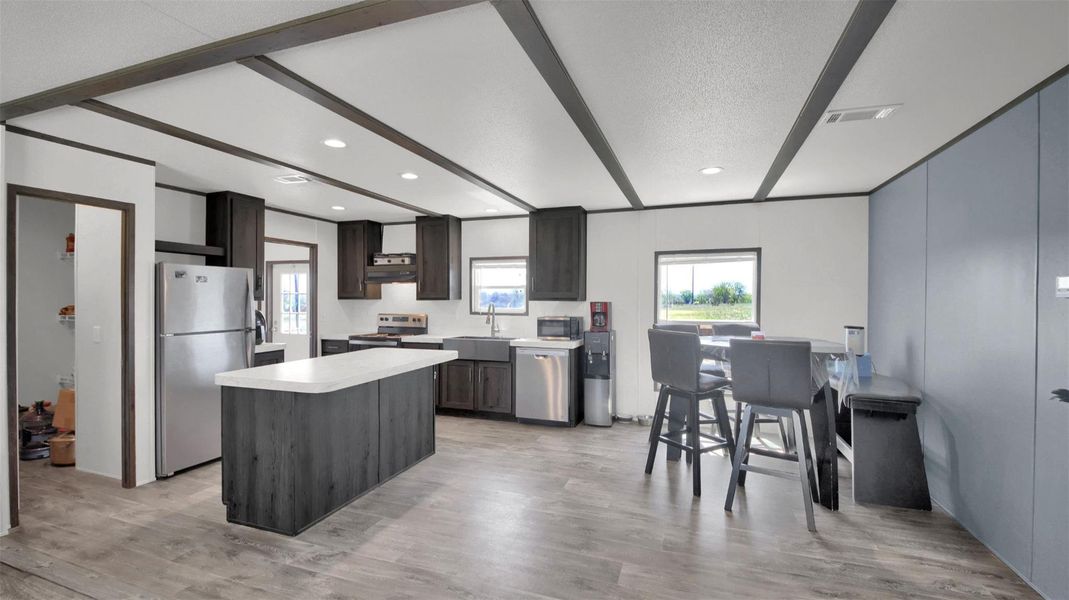 Kitchen with stainless steel appliances, light countertops, plenty of natural light, a center island, and a textured ceiling