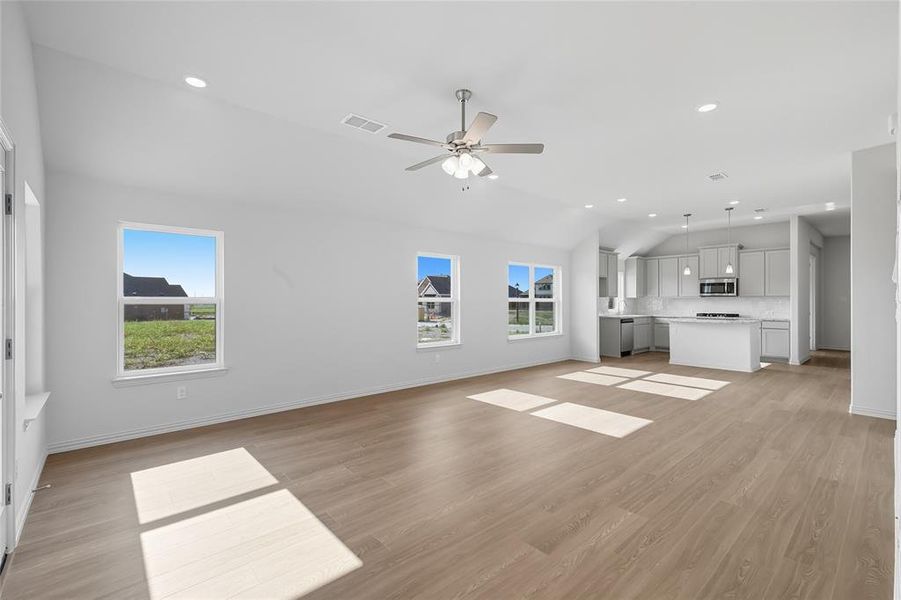 Unfurnished living room featuring recessed lighting, light wood finished floors, healthy amount of natural light, vaulted ceiling, and a ceiling fan Unfurnished living room featuring recessed lighting, light wood finished floors, healthy amount of natural light, vaulted ceiling, and a ceiling fan
