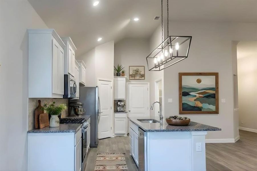 Kitchen with white cabinetry, tasteful backsplash, light wood finished floors, appliances with stainless steel finishes, and pendant lighting Kitchen with white cabinetry, tasteful backsplash, light wood finished floors, appliances with stainless steel finishes, and pendant lighting