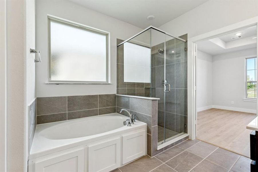 Bathroom featuring vanity, a bath, light tile patterned flooring, and a stall shower Bathroom featuring vanity, a bath, light tile patterned flooring, and a stall shower