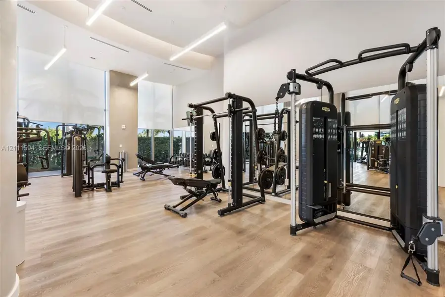 Fitness center featuring wood-finish flooring, floor-to-ceiling windows, and recessed lighting Fitness center featuring wood-finish flooring, floor-to-ceiling windows, and recessed lighting
