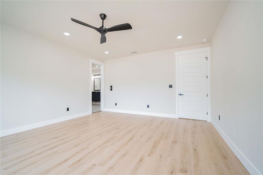Spacious room featuring light wood-finish flooring, recessed lighting, and a modern black ceiling fan