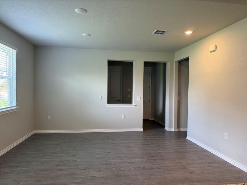 Recessed lighting illuminates this versatile living area, showcasing its attractive flooring and window blinds.