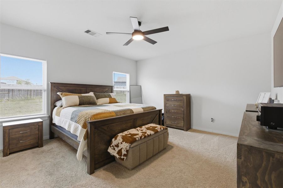 Bedroom featuring light carpet, multiple windows, and ceiling fan