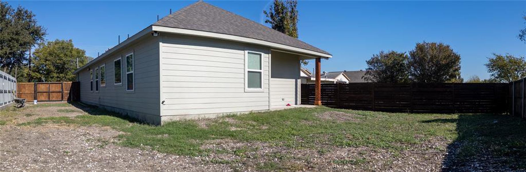 View of side of home with a fenced backyard and roof with shingles